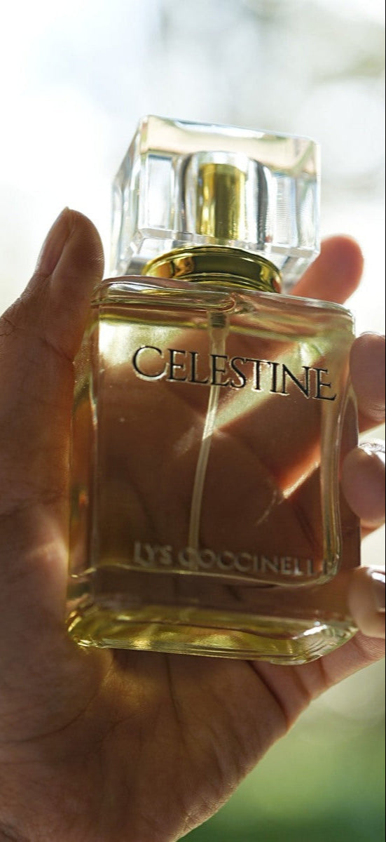 Hand holding a bottle of Celestine perfume with a blurred natural background
